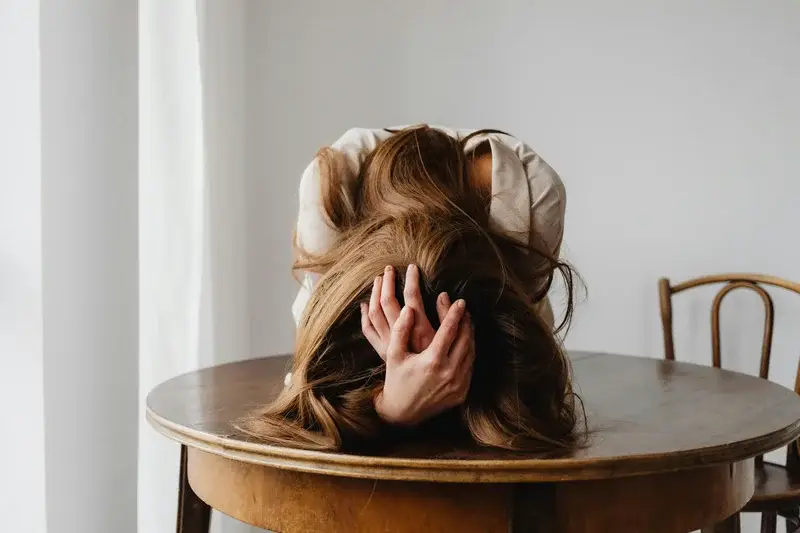 Femme la tête dans les mains, symbole de stress et d’anxiété.