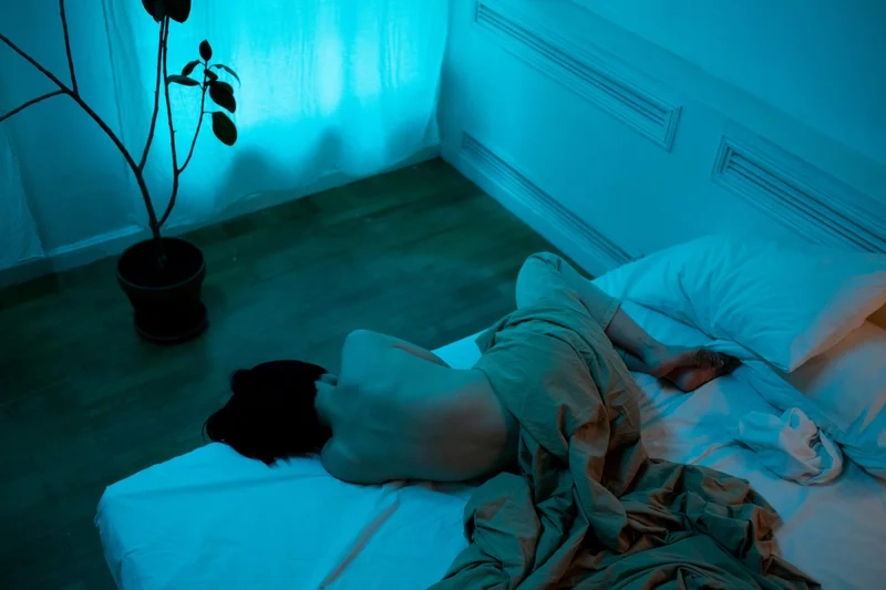 Personne allongée dans une chambre sombre – illustration du traitement des troubles du sommeil par l’hypnose ericksonienne.